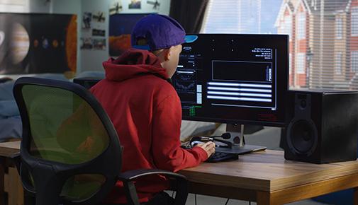 View from behind of boy using computer to code